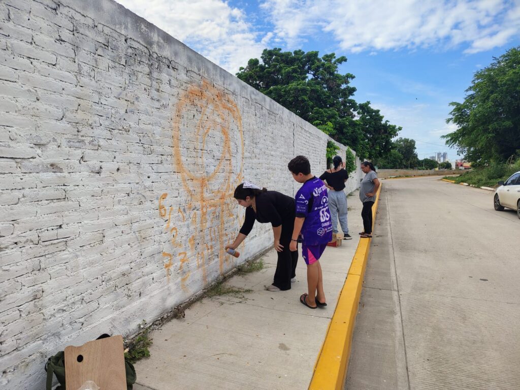Jóvenes pintan paredes con murales
