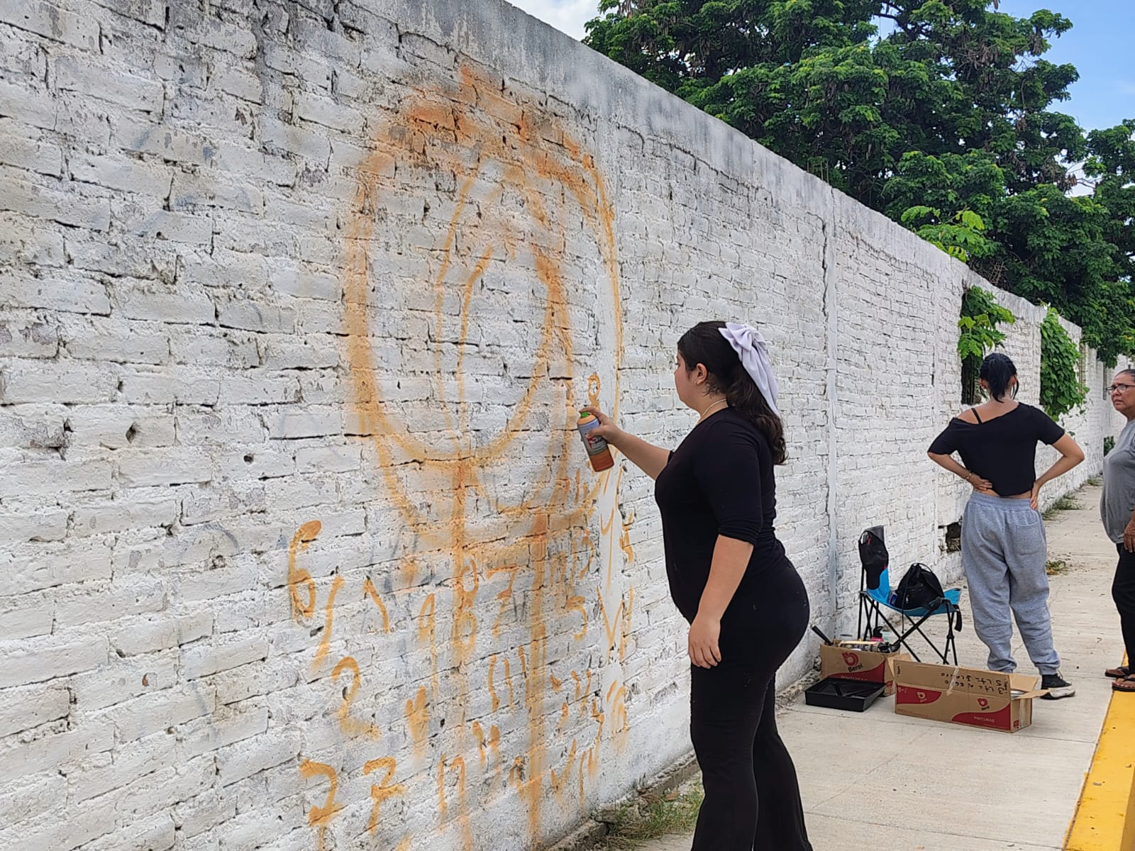 Jóvenes pintan paredes con murales