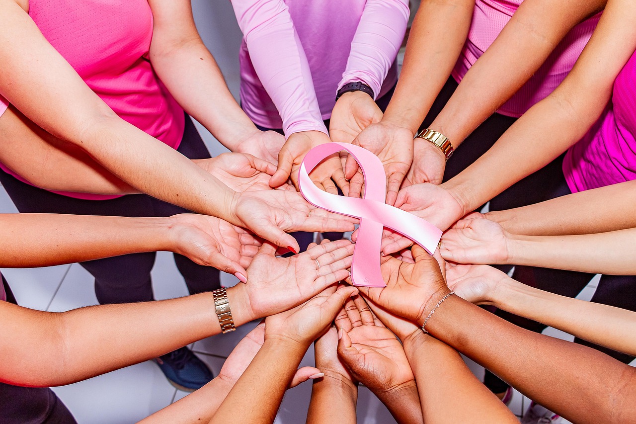 Mujeres sosteniendo un listón rosa alusivo al mes de la lucha contra el cáncer de mama.