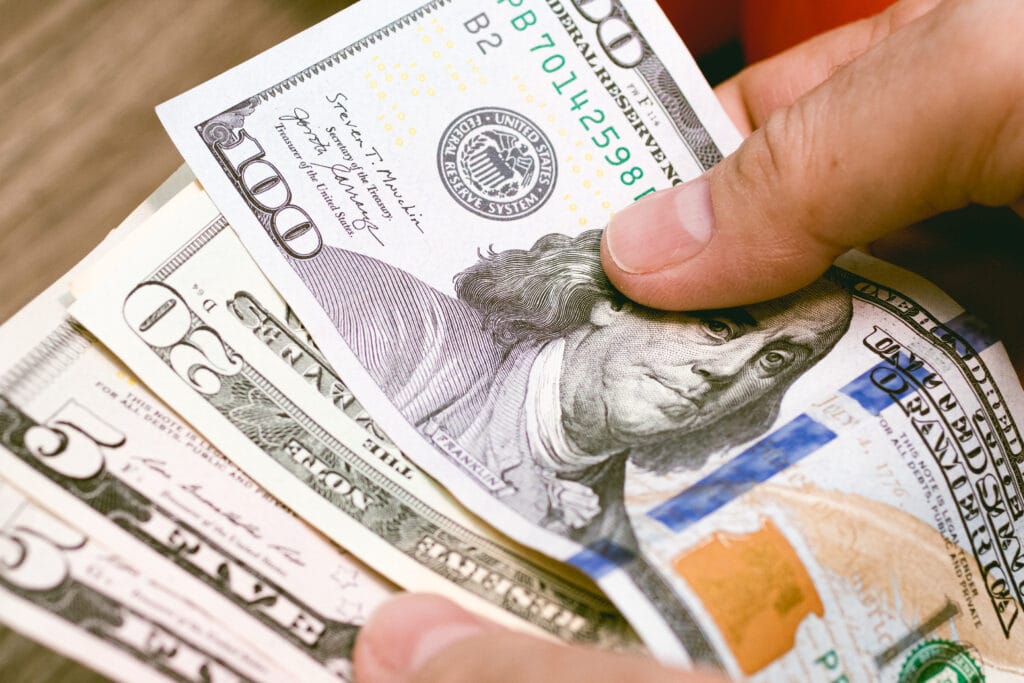 Billetes de dólar en los dedos de una persona