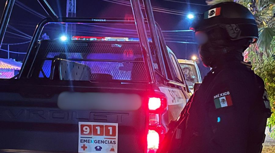 Elemento policiaco junto a una patrulla con las luces encendidas