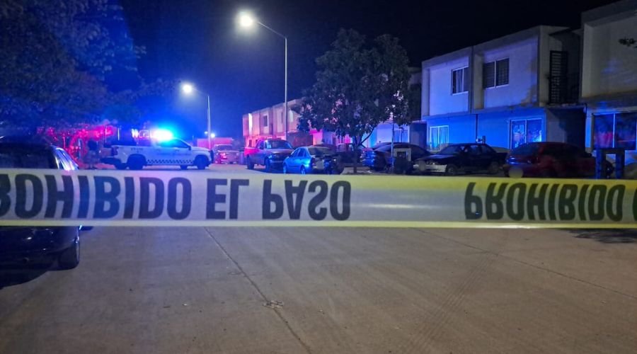 Cinta amarilla de precaución en una calle, al fondo se observa una unidad de la Guardia -nacional y luces color rojo y azul