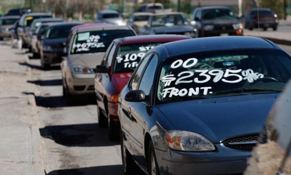 Varios autos en venta estacionados con el precio escrito en el vidrio