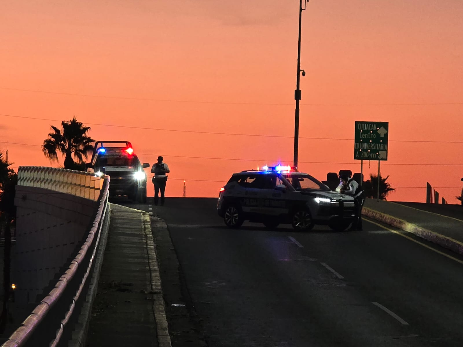 Cielo naranja por el amanecer, 2 patrullas y elementos de emergencias en la zona del accidente sobre una calle