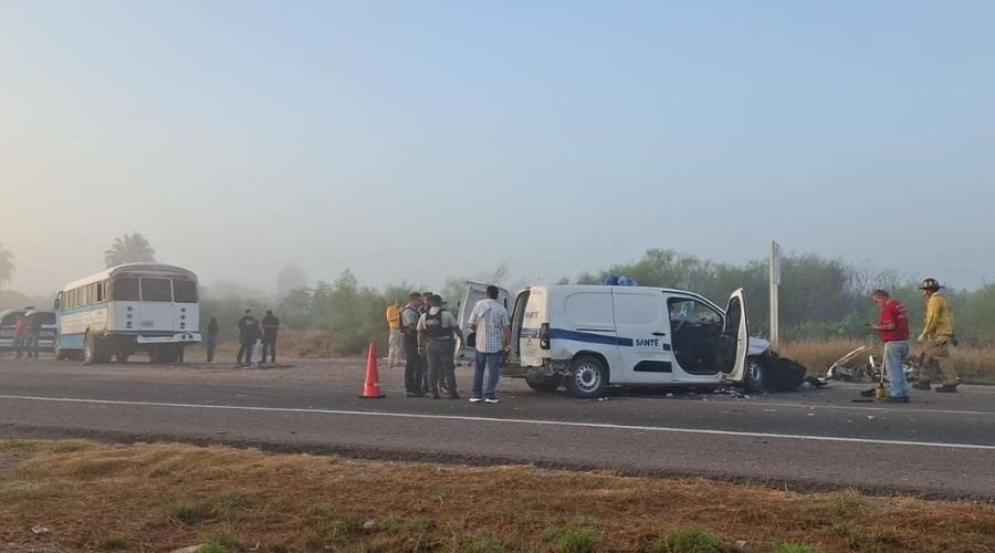 Escena de accidente, se observa una vagoneta con el frente destruido y un camión de en colores blanco y azul, hay personas y entre ellos bomberos