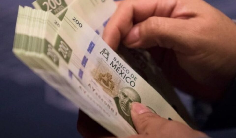 Manos sosteniendo una gran cantidad de billetes de doscientos pesos