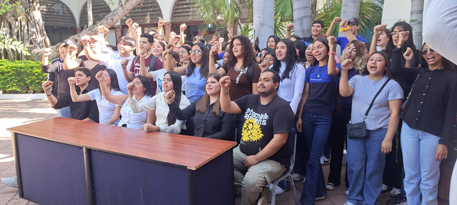Alumnos de la UAS reunidos y levantando sus brazos mientras expresan un mensaje