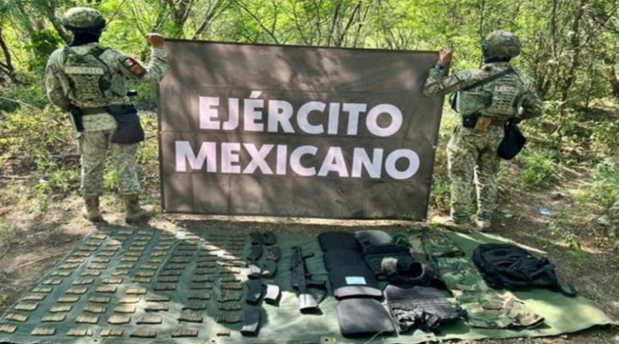 Dos elementos del Ejercito Mexicano de espaldas sosteniendo una lona con la leyenda del ejercito y en el suelo colocado todo lo que encontraron en el operativo realizado en concordia