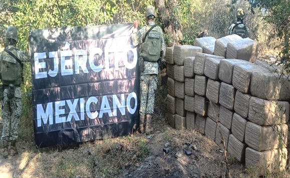 Militares sosteniendo una lona y a un lado los paquetes de mariguana asegurados durante el operativo