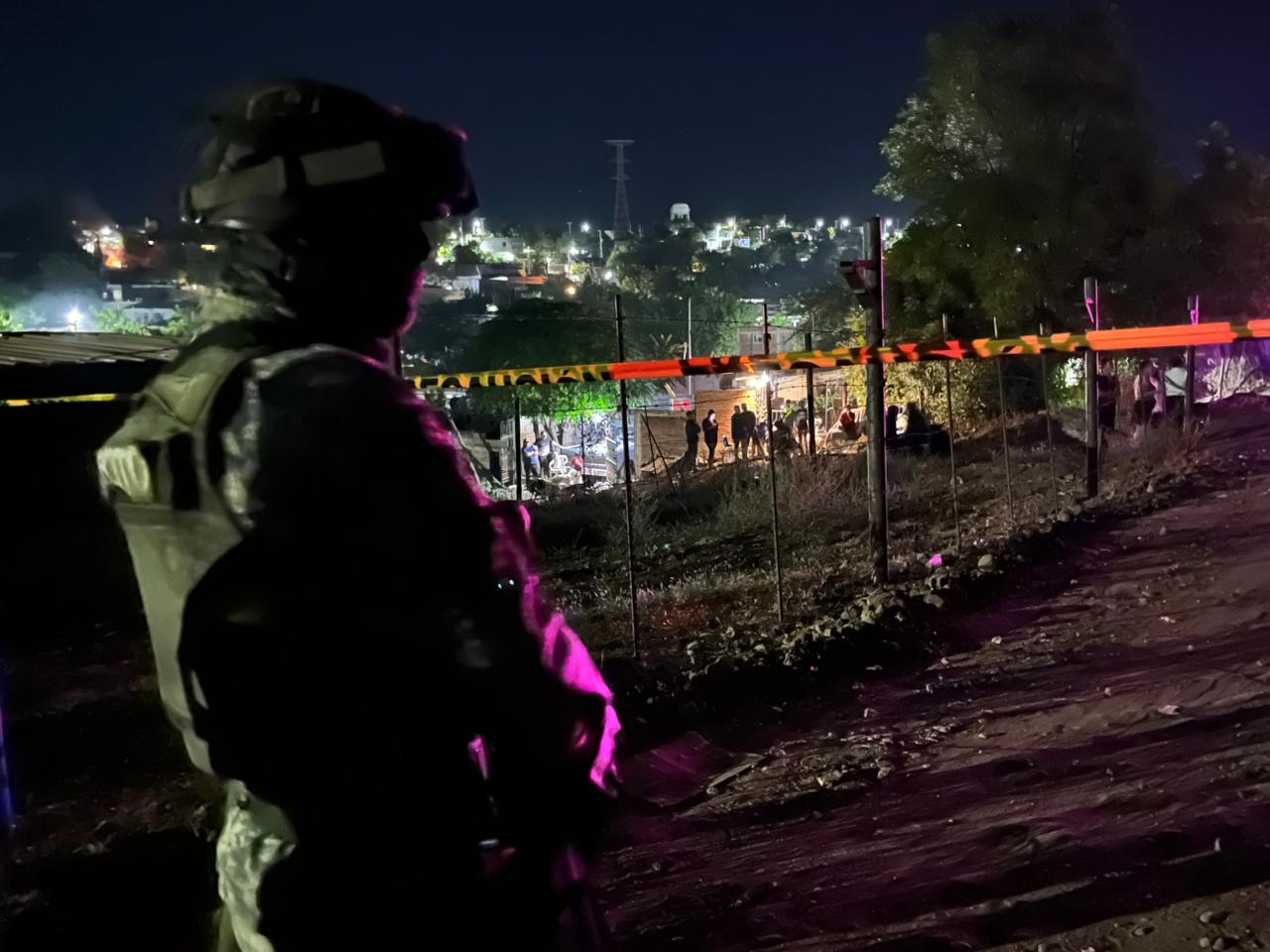 Militar parado atrás de una zona acordonada, al fondo hay autoridades investigando