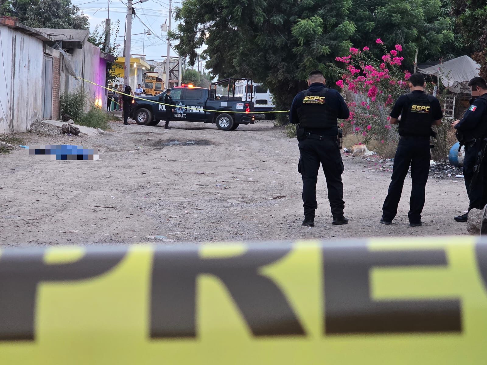 Cinta amarilla, policías anotando cosas y un cuerpo tirado en la calle