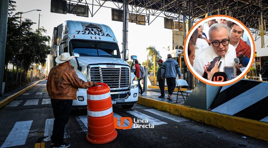 Caseta de peaje con un trailer parado, una persona con sombrero parado junto a un cono naranja en el paro por productores