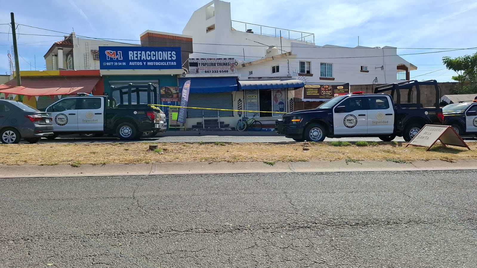 Patrullas de Seguridad afuera de unos negocios. Hay una zona acordonada afuera de una barbería