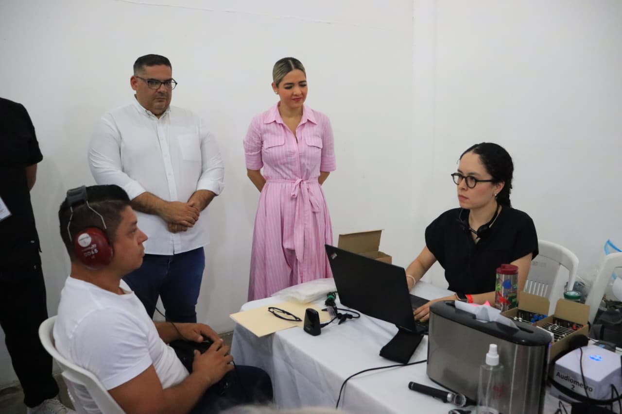 Estrella Palacios Domínguez alcaldesa de Mazatlán junto a equipo de DIF Mazatlán y Beneficencia Pública, proporcionando apoyo auditivo a un ciudadano