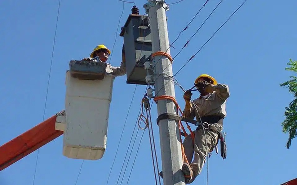 Trabajadores de la Comisión Federal de Electricidad (CFE) arreglando un transformador en un poste de luz