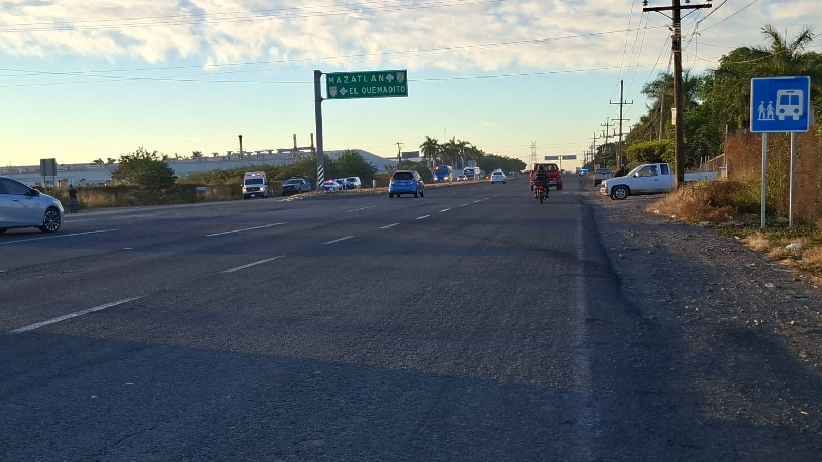 Carretera con carros transitando, al fondo se observan unidades de emergencia en una zona en la que localizaron a una persona con heridas de bala