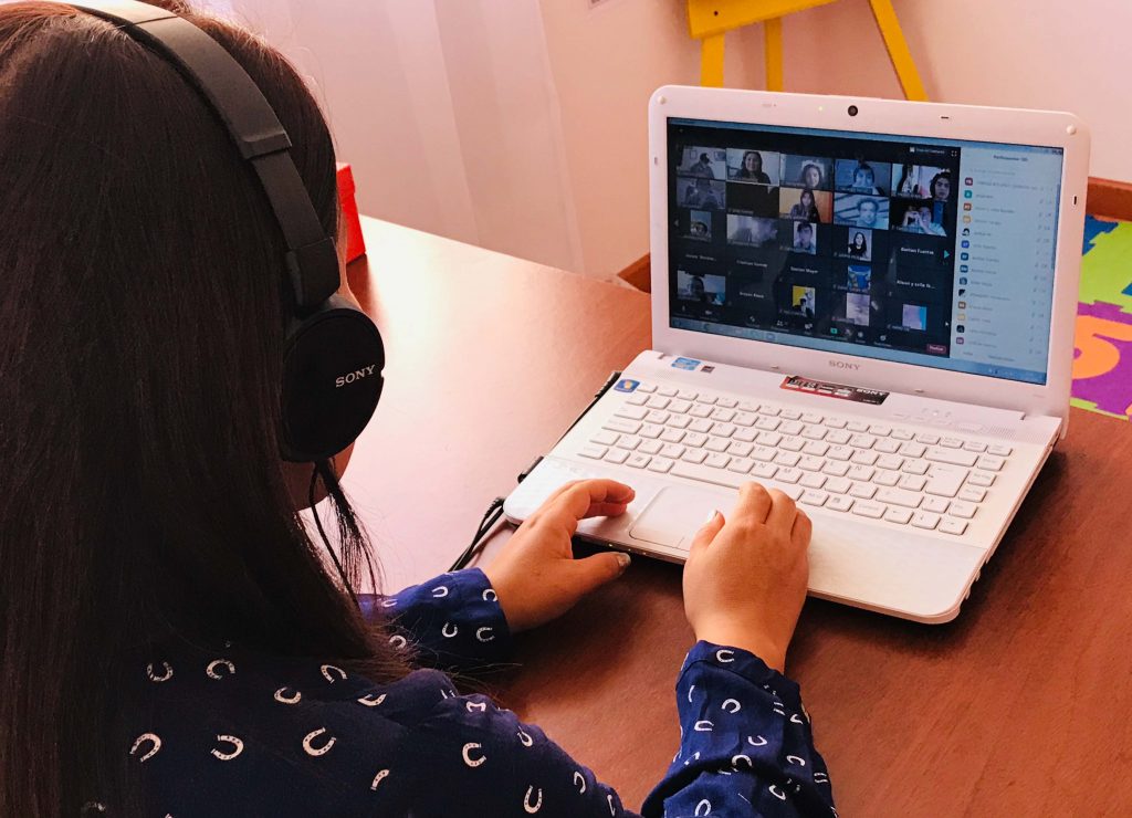 Niña con audifonos frente a una computadora