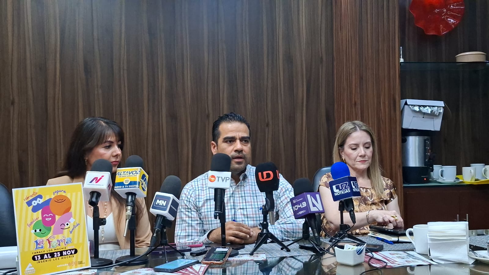 Empresarios sentados en una mesa con micrófonos realizando una rueda de prensa
