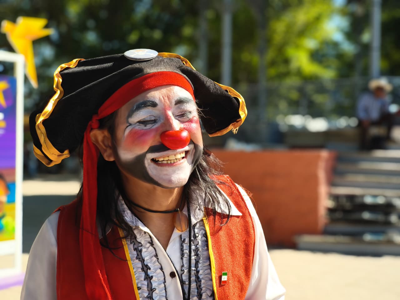 Cuentacuentos Claudio Trejo caracterizado de payaso, con un sombrero pirata y sonriendo mirando hacia un costado