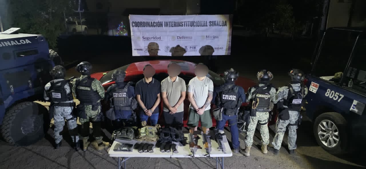 Cuatro elementos de PEP volteados sosteniendo una lona y en el medio los 4 detenidos en Culiacán