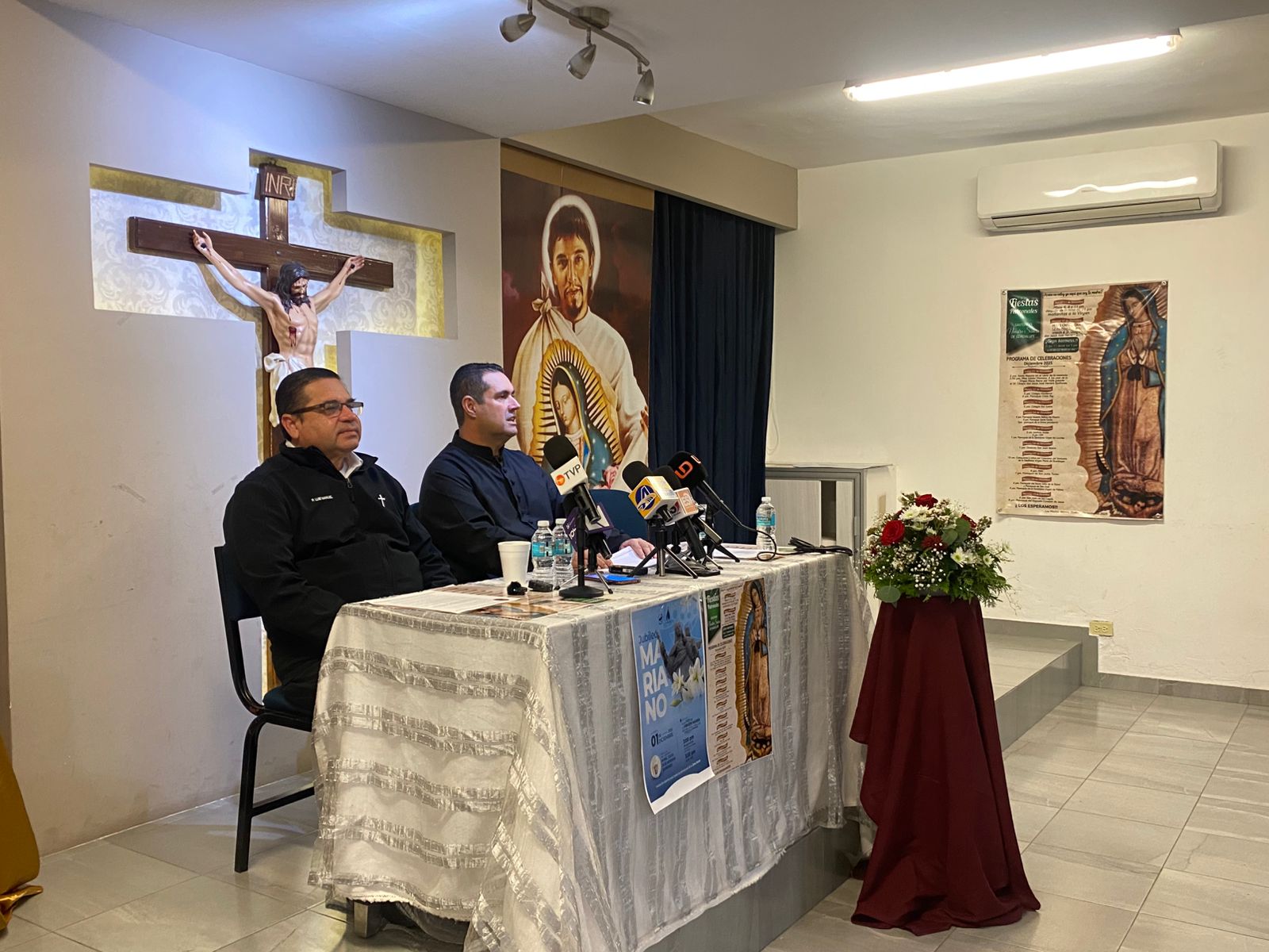 sacerdote Jesús Ibarra Ramos en una mesa con monseñor anunciando el itinerario para el Día de la Virgen