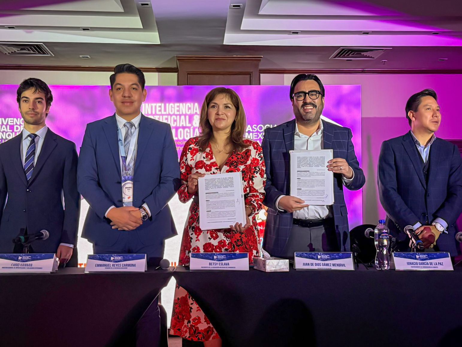 Personas de pie en una rueda de prensa mostrando un documento