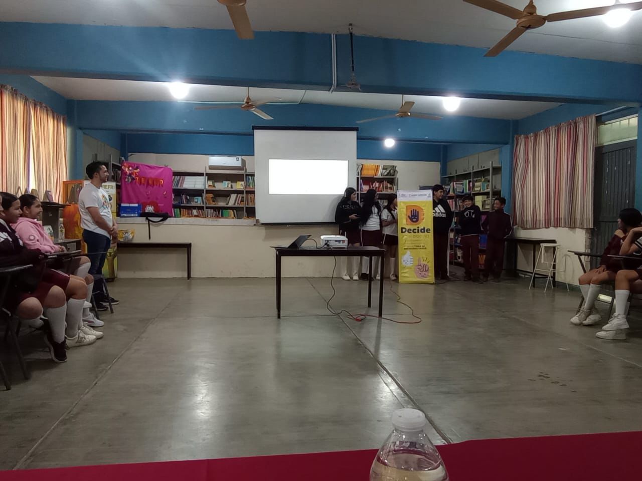 Estudiantes dentro de un aula de clases exponiendo unas diapositivas sobre el tema de la salud emocional.