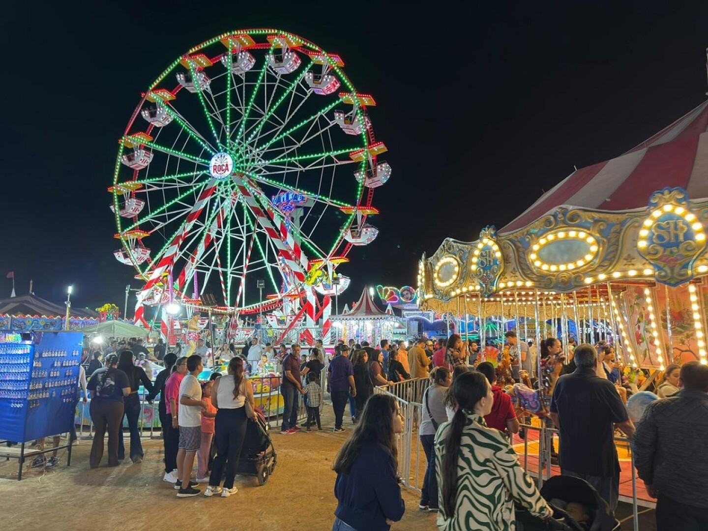 Personas en una feria con una rueda de la fortuna