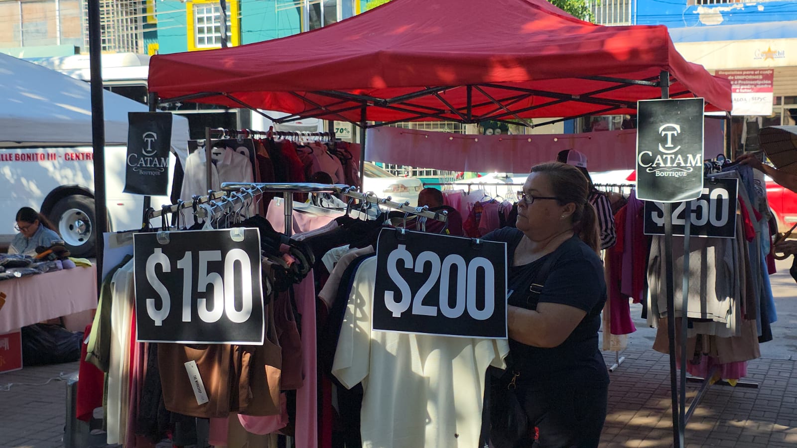 Festival de las Liquidaciones 2025: ropa en ganchos en venta, bajo una carpa de color rojo
