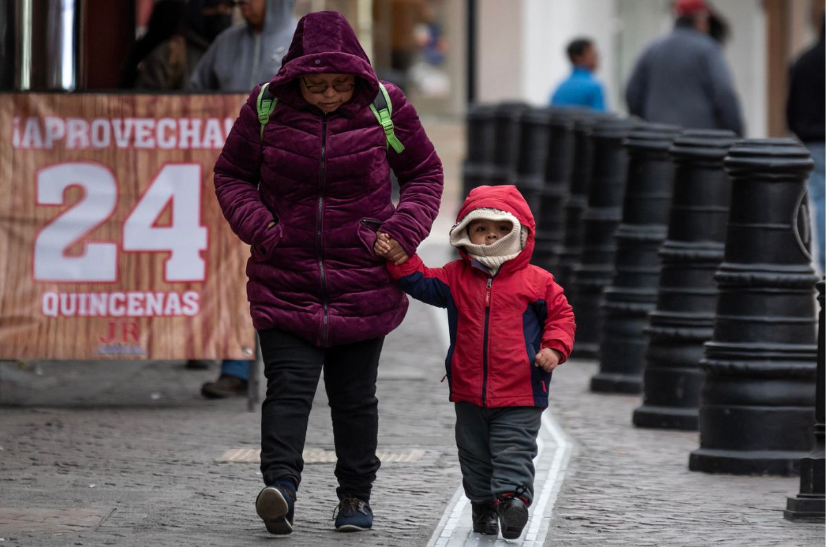 PErsona adulta con un niño caminando agarrados d ela mano con sueter y chamarra por el frío