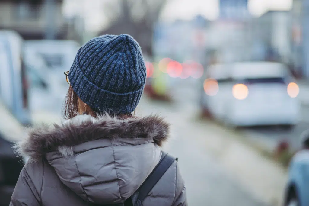 Mujer de espaldas caminando y usando una chamarra y un gorro