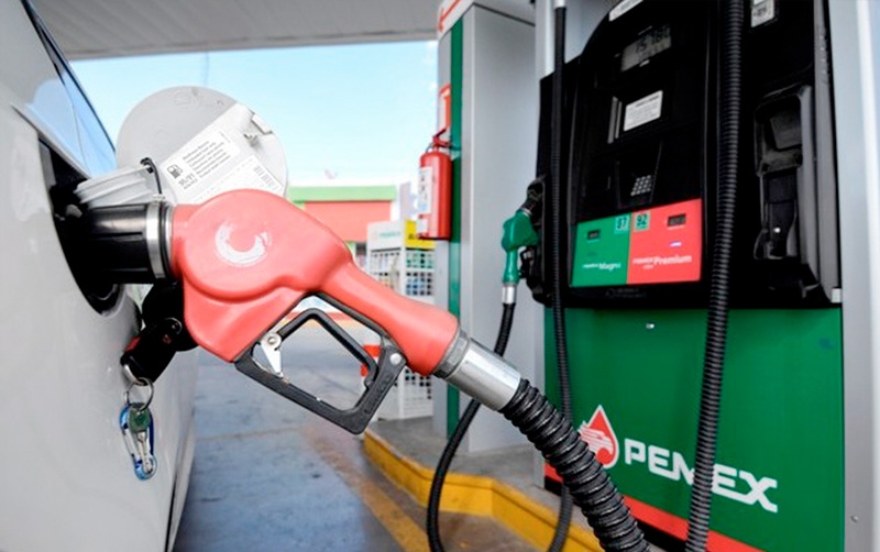 estación de gasolina, una manguera dispensadora de gasolina color rojo en la boca del tanque de un carro
