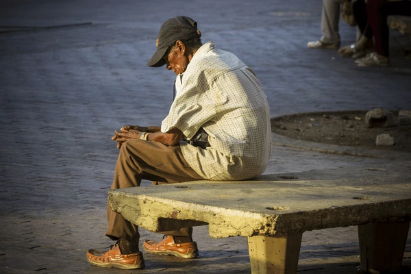 Hombre adulto sentado en una banca.