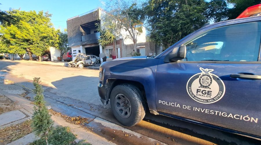 Unidad de la FGE y al fondo personas y una casa incendiada junto a un automovil calcinado