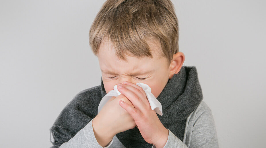 Niño enfermo sonándose la nariz