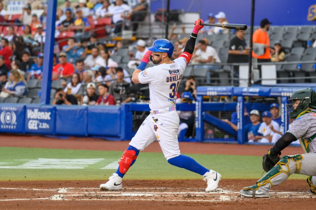 Julián Ornelas en la caja de bateo haciendo swing a una pelota, por detrás el cátcher de Cañeros de Los Mochis esperando para recibir el lanzamiento de su Pitcher