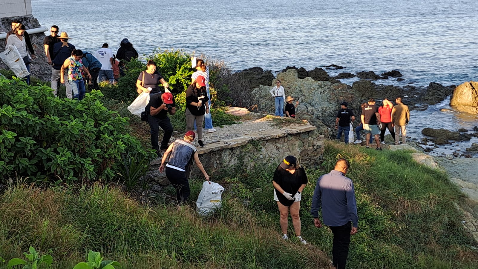 Muchas personas a orilla de playa en Mazatlán levantando basura