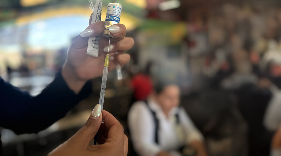 Manos de una mujer sosteniendo una jeringa y un medicamento