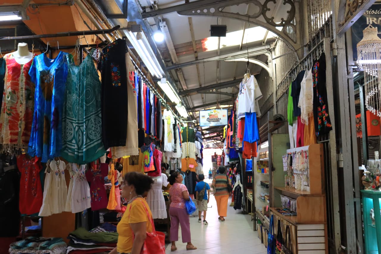 Pasillo de un mercado con negocios de ropa, bolsas y accesorios, entre otros objetos.
