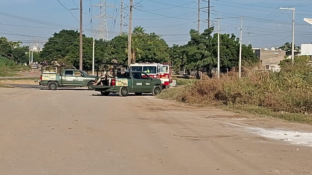 Dos camionetas del ejército junto a un camión de bomberos en calle de terracería con una cinta amarilla
