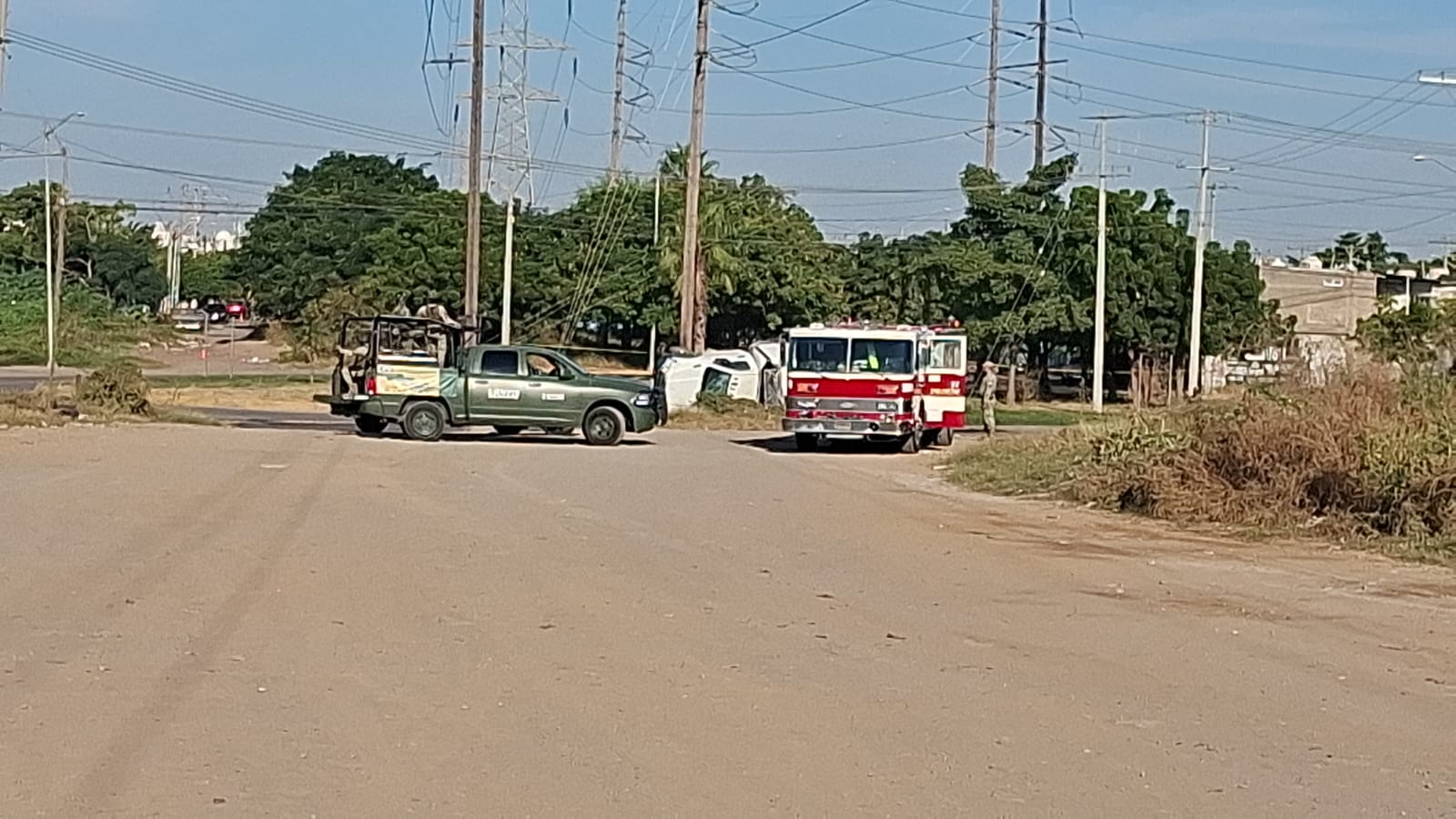 Una unidad del ejército mexicano junto a un camión de bomberos en calle de terracería