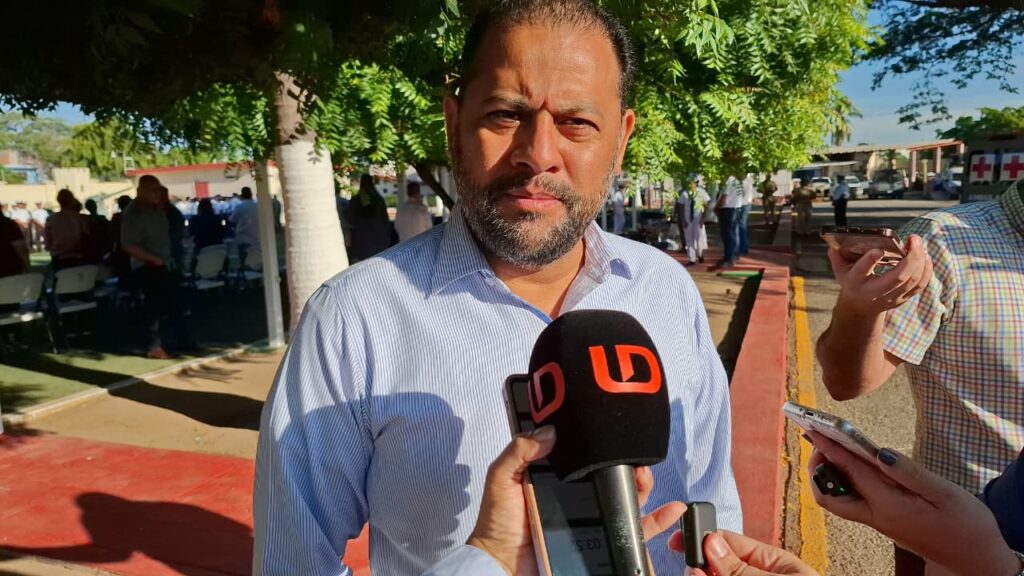 Persona de frente usando una camisa color blanco atrás de un micrófono color negro con las letras LD color naranja