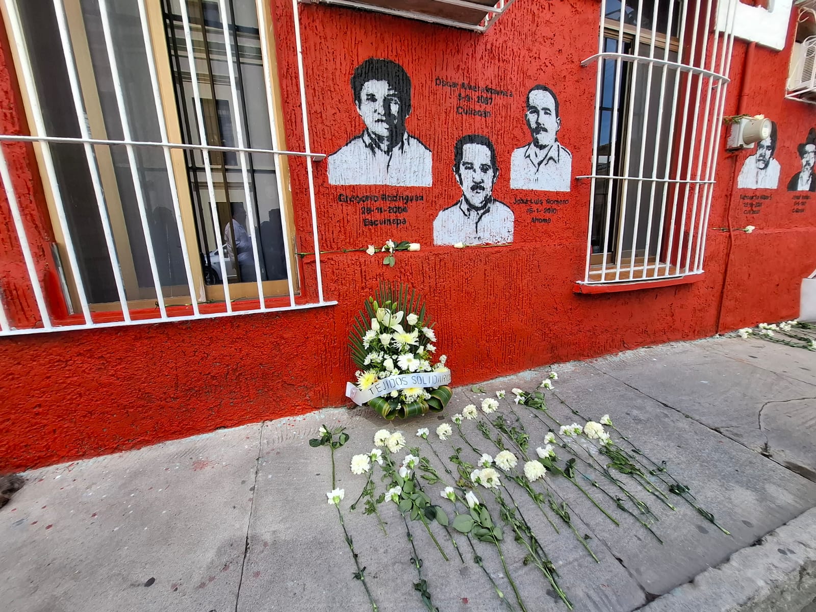 Periodistas que han sido asesinados pintados en un mural y una corona de flores