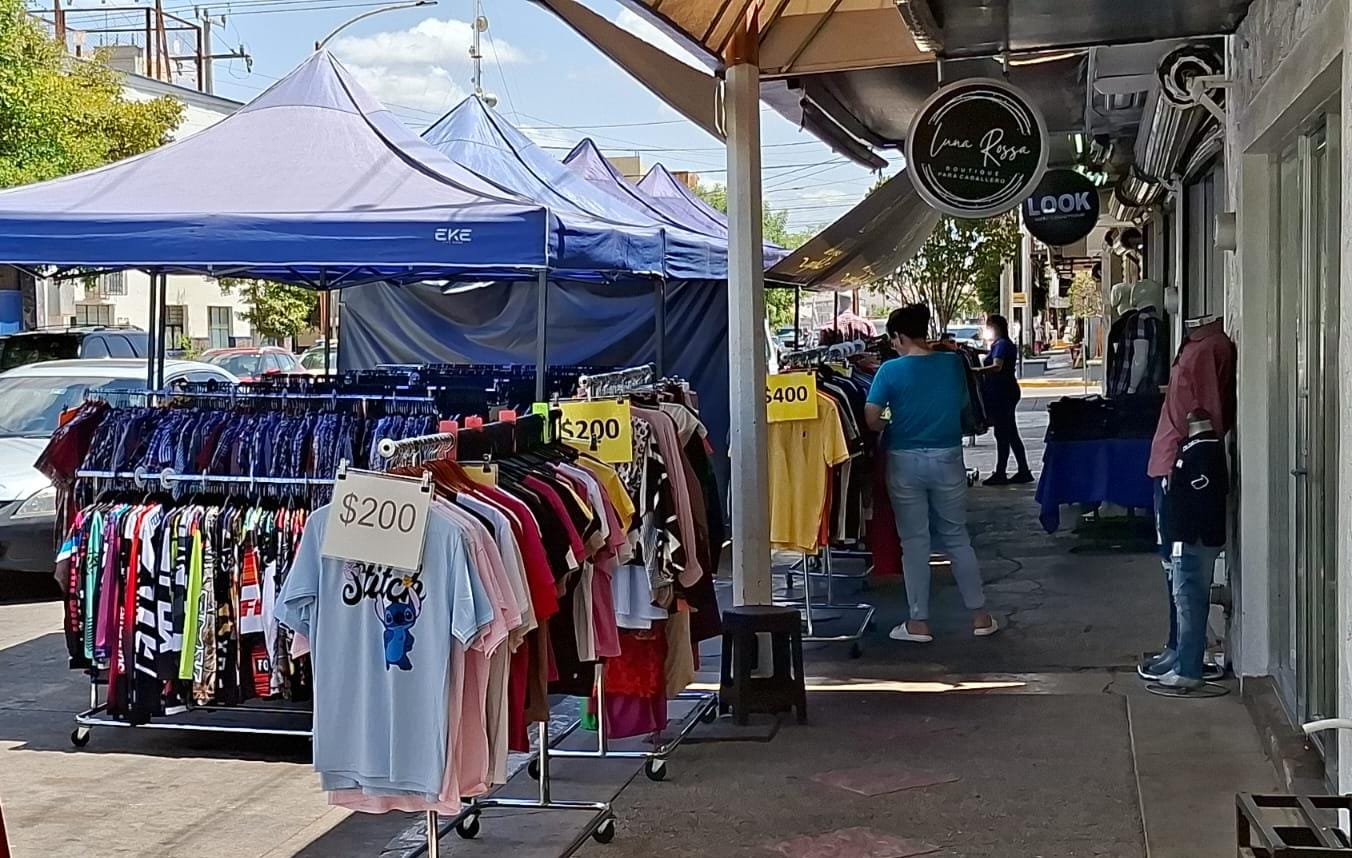 Tienda de ropa con estantes y personas viendo