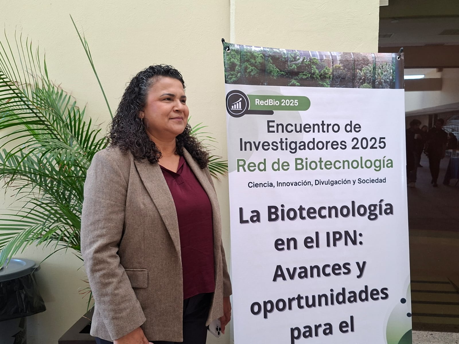 Norma Elena Leyva López junto a un banner del evento