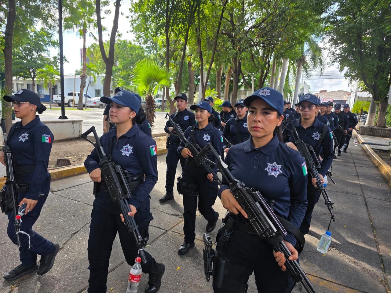 Nuevos policías de Culiacán formados en filas, marchando por la calle con armas y uniforme