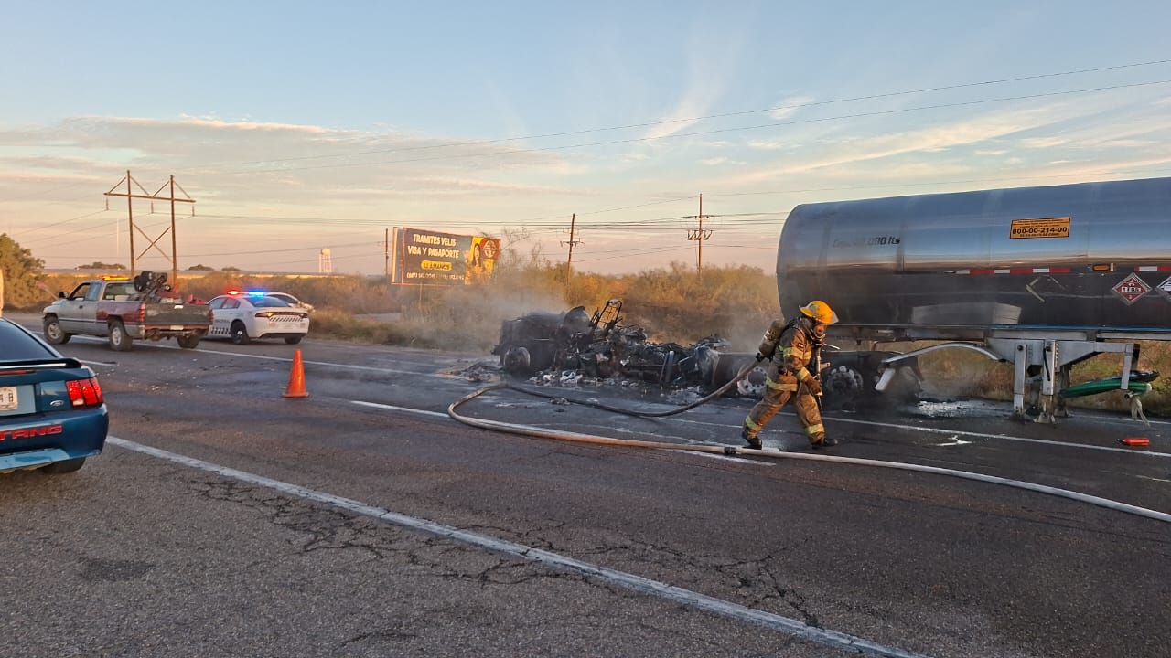 Carretera, vehiculos y una pipa entre humo por el incendio además de un bombero arrastrando una manguera