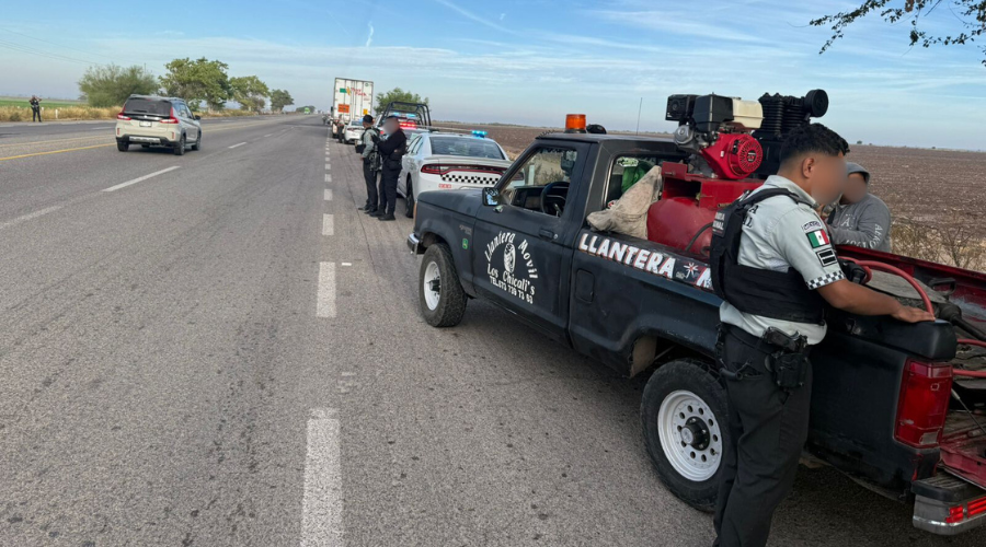 Unidades de la guardia nacional y autos estacionados al lado de una carretera, una camioneta de una llantera al principio de la hilera de carros