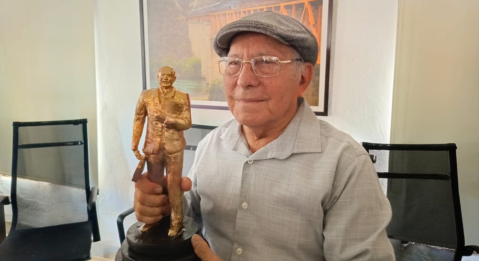 Profesor César Gamez junto a reconocimiento o estatuilla
