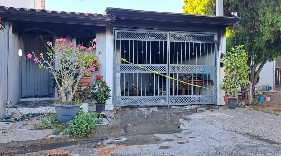 Fachade de casa blanca con portón negro y plantas en la banqueta, quemada por delincuentes en Culiacán